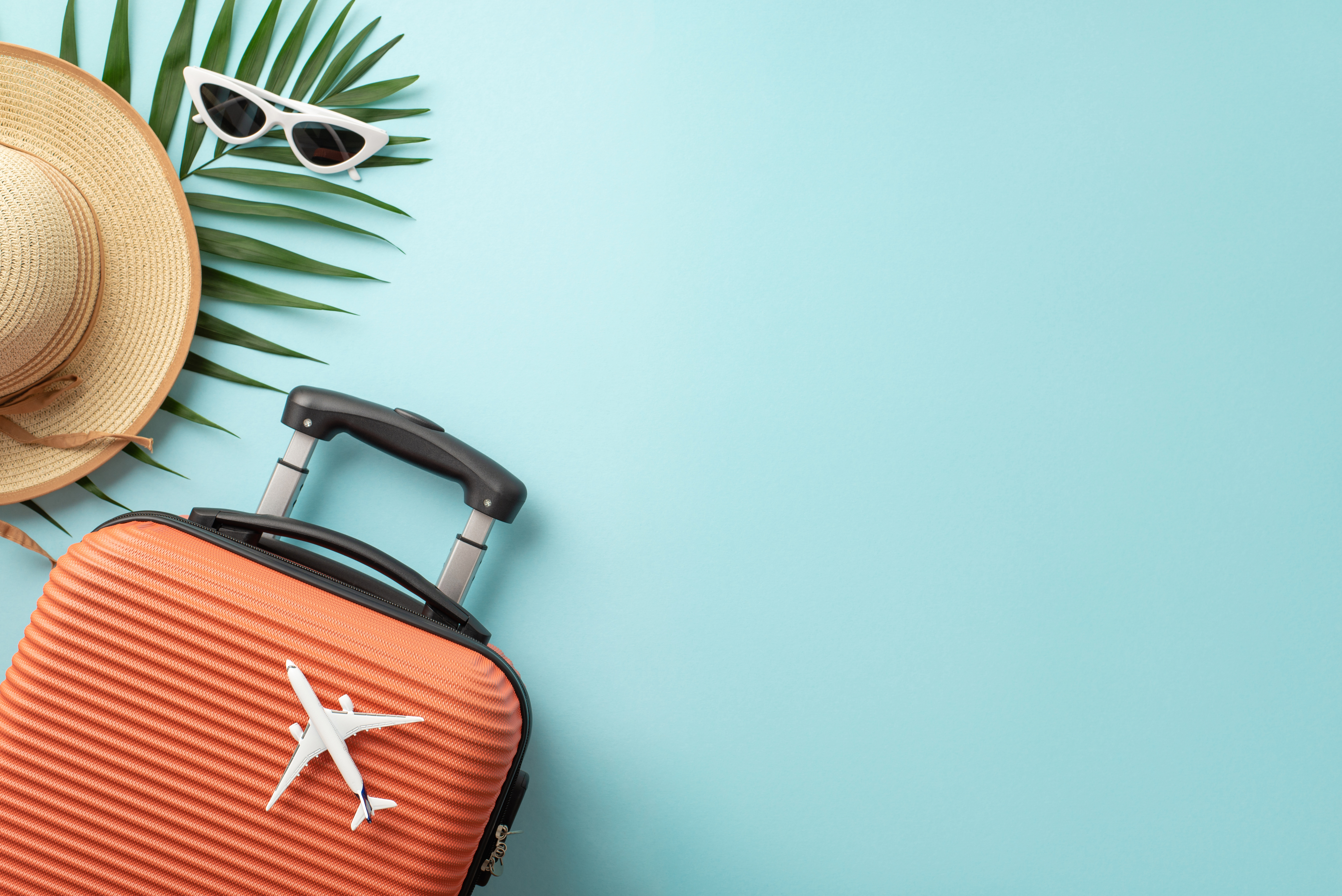 Travel essentials — suitcase, sun hat, sunglasses